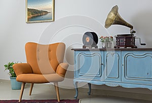 Retro orange armchair, vintage wooden light blue sideboard, old phonograph gramophone and vinyl records