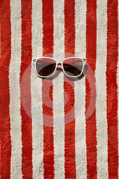 Retro pair of sunglasses on red and white striped beach towel