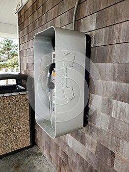 Retro partial payphone outside on brown shingle wall