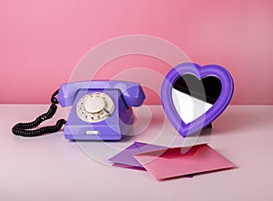 Retro phone on table with heart-formed mirror and envelopes. Valentine s day and love concept