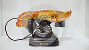 Retro phone with unusual handset. Action. Black retro phone with crab shaped handset stands on white Museum window