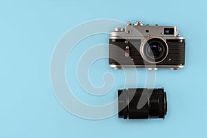 Retro photo camera with lens on blue background, top view