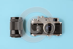 Retro photo camera with lens on blue background, top view