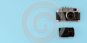 Retro photo camera with lens on blue background, top view