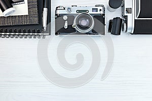 retro photo cameras, frame, notebook, pen, negative films on white wooden background