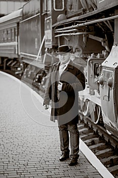 Retro photo of elegant man waiting on platform for train