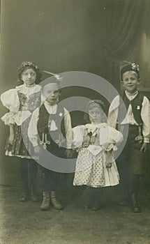Retro photo shows cihldren wear traditonal folk costum. Vintage black and white photography. Circa 1930.