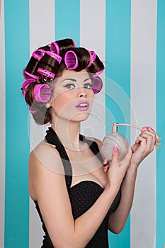 Retro pin up girl spraying perfume with hair rollers