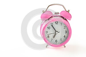 Retro pink alarm clock, with 5 minutes to 7 o`clock on it. Isola