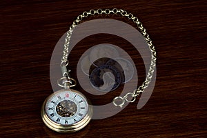Retro Pocket Watch and Chain with Old Victorian Pennies on a Polished Wooden Surface