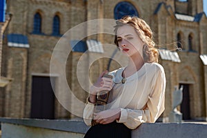 Retro portrait of a beautiful dreamy girl holding a book in hands outdoors. Soft vintage toning.