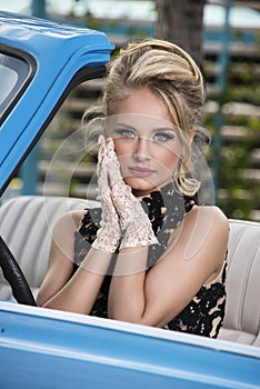 Retro portrait of gorgeous blonde in a blue car