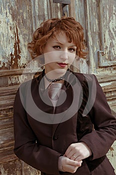 Retro portrait of red haired women in vintage coat agains obsolete wooden background