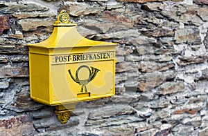 A retro postbox in yellow color in Marksburg, Germany.