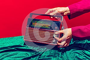 Retro radio. Female hand touching radioreceiver  on red and green background. Vintage, retro fashion style. Pop