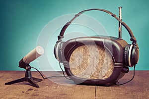 Retro radio, headphones and microphone on wooden table front mint blue background. Vintage style photo