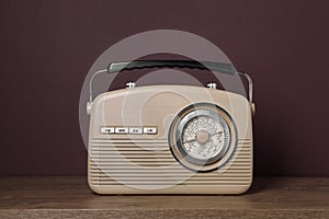 Retro radio receiver on wooden table against brown background