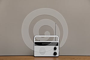 Retro radio receiver on wooden table against grey background