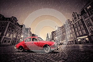 Retro red car on cobblestone historic old town in rain. Wroclaw, Poland.