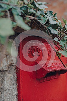 Retro red mailbox in Cotswolds, UK, selective focus, framed by an ivy plant