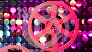 Retro reel with film rotating on colorful shining sparkles wall. Old-fashioned 8mm film projector playing in glitter