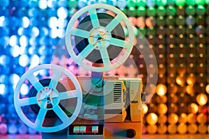 Retro reel with film rotating on colorful shining sparkles wall. Old-fashioned 8mm film projector playing in glitter