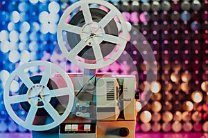 Retro reel with film rotating on sequins kinetic wall, colorful light. Old-fashioned 8mm projector playing in decorated