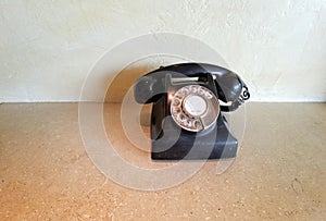 Retro rotary black dial telephone with Chinese and Arabic numerals on the marble table on wall background with copy space