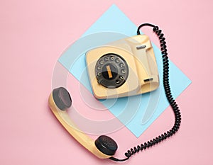 Retro rotary phone from 80s on a colored pastel background. Top view, minimalism.