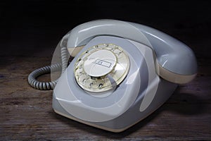 Retro rotary telephone of gray plastic with rotary dial on a dar