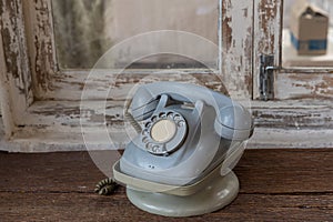 Retro rotary telephone on wood table. Vintage telephone. grey old phone. Retro telephone on table in front windows background.