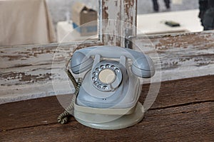 Retro rotary telephone on wood table. Vintage telephone. grey old phone. Retro telephone on table in front windows background.