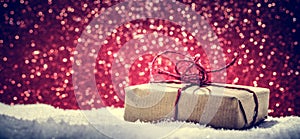 Retro rustic Christmas gift, present in snow on glitter background