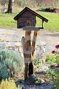 Retro rustic newly made decorative wooden birdhouse made in shape of wooden log cabin with front porch on top of tree stump