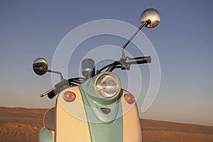 Retro scooter at sunset in the golden sand of the Namib Desert