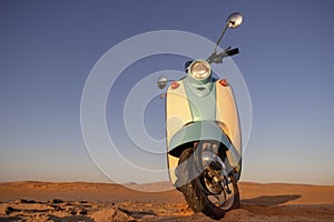 Retro scooter at sunset in the golden sand of the Namib Desert