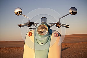 Retro scooter at sunset in the golden sand of the Namib Desert