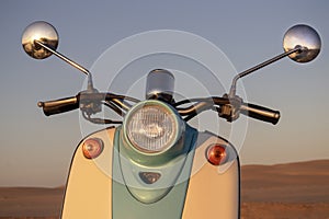 Retro scooter at sunset in the golden sand of the Namib Desert