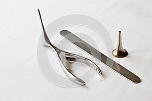 Retro. A set of steel medical instruments for examination of the ear, throat, nose. White gauze background.