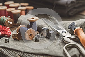 Retro sewing items: tailoring scissors, cutting knife, thimble, wooden thread spools, cushion for including pins, sewing accessori photo