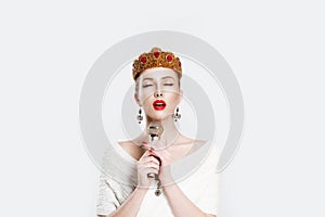 Retro singer. Beauty queen speaking singing karaoke on microphone isolated white background wall. Angry Girl with golden ruby