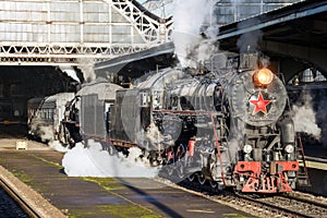 Retro steam locomotive train stands on the railway station.