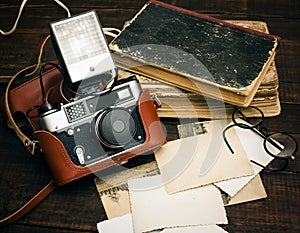 Retro still camera and some old photos on wooden table background