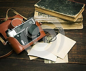 Retro still camera and some old photos on wooden table background