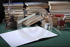 Retro still life. On the desktop, there are: a kerosene lamp, hourglass, penholder, old ink-bottle and old books.