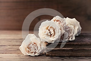 Retro still life with vintage rose flowers and ancient book. Nostalgic composition on old wooden table. photo