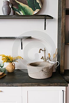 Retro stone sink and mixer golden in the kitchen in the Scandinavian style, a bouquet of mimosa in a clay vase