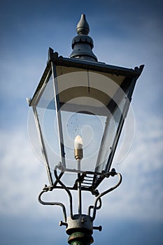 Retro street lamp shining against cloudy sky background