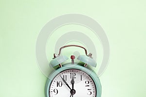 Retro style alarm clock over the mint green background