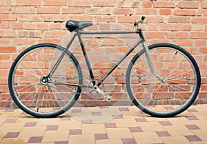 Retro style bicycle against brick wall, vintage tinted photo